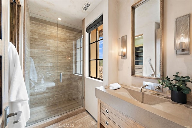 bathroom with a stall shower, visible vents, wood finished floors, and vanity