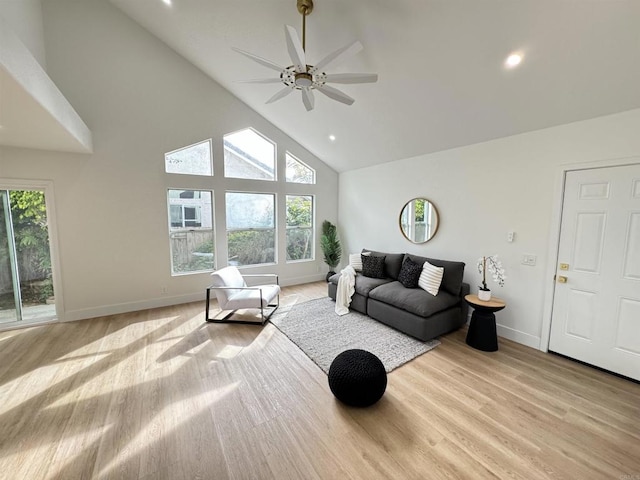 living area with light wood-type flooring, plenty of natural light, high vaulted ceiling, and baseboards