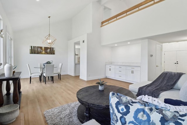 living area with light wood-type flooring, baseboards, and high vaulted ceiling