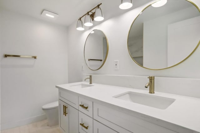 full bathroom featuring double vanity, a sink, toilet, and baseboards