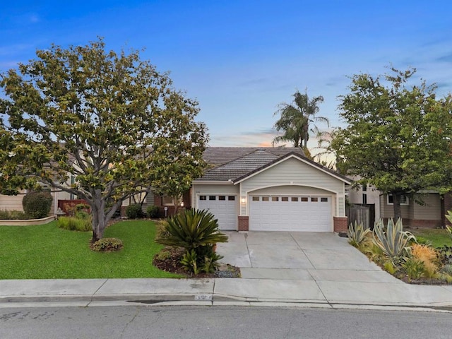 view of front of home featuring an attached garage, brick siding, concrete driveway, a tiled roof, and a front lawn