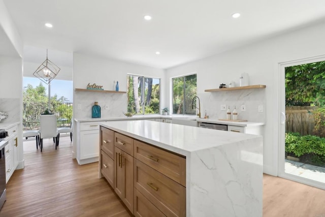 kitchen with a kitchen island, a sink, white cabinetry, open shelves, and backsplash