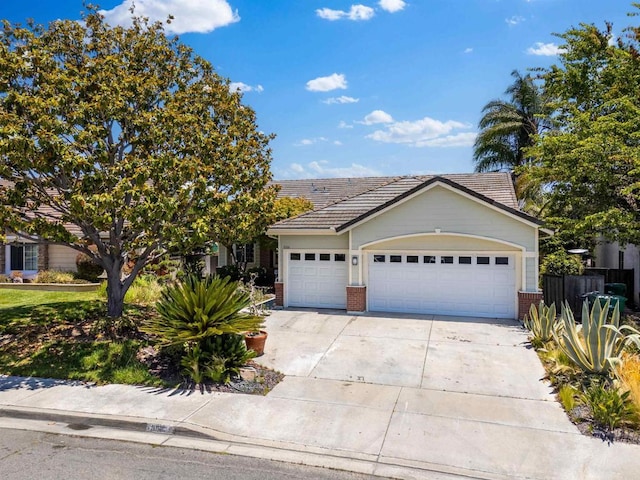 view of front of house with an attached garage, a tile roof, concrete driveway, and brick siding