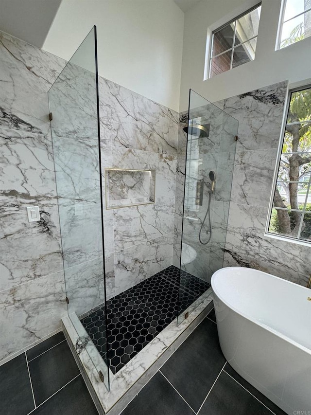 bathroom with a soaking tub, a marble finish shower, tile walls, and tile patterned floors