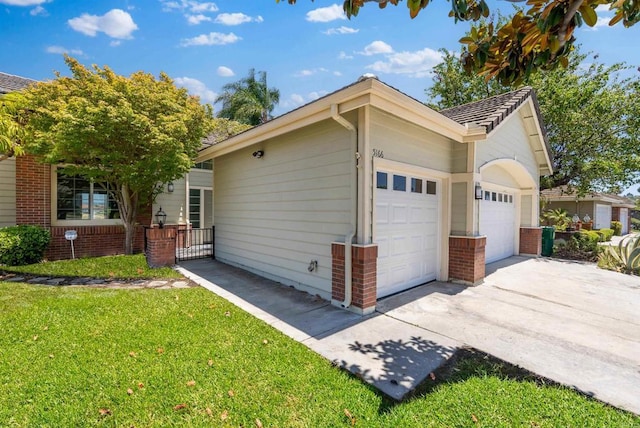 view of home's exterior featuring a garage, driveway, brick siding, and a yard