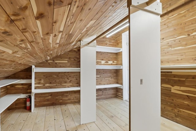 interior space featuring vaulted ceiling, wooden ceiling, wood walls, and wood finished floors