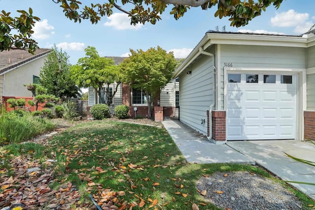 view of side of home featuring an attached garage, brick siding, and a yard