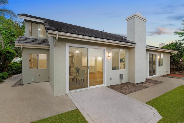 back of property featuring a patio area, a chimney, and stucco siding