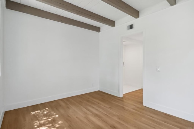 unfurnished room with beam ceiling, visible vents, light wood-style flooring, and baseboards