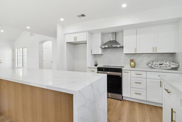 kitchen with electric range, a kitchen island, white cabinets, wall chimney range hood, and backsplash