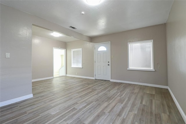 foyer entrance featuring baseboards, visible vents, and light wood finished floors