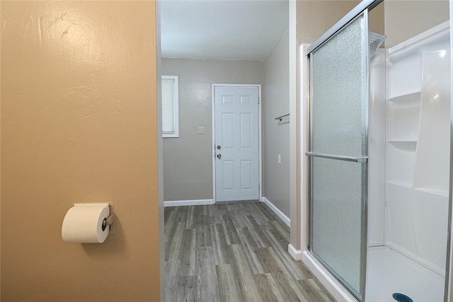 bathroom featuring a stall shower, wood finished floors, and baseboards