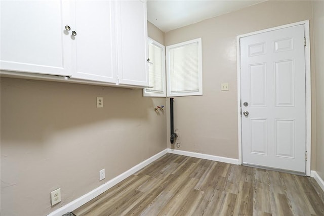 laundry area featuring light wood-style floors, cabinet space, and baseboards