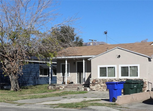 ranch-style house featuring covered porch and stucco siding