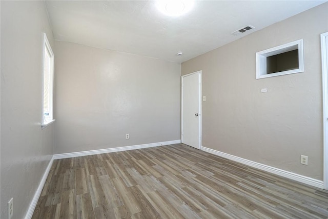 unfurnished room featuring light wood finished floors, visible vents, and baseboards