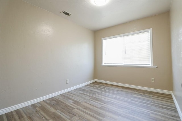 spare room with light wood-type flooring, baseboards, and visible vents