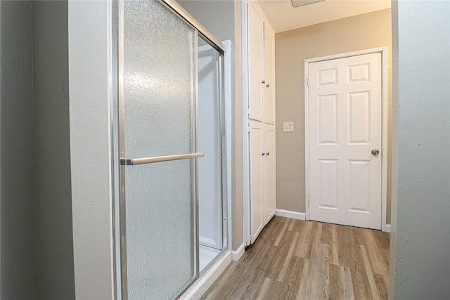 bathroom featuring a shower stall, baseboards, and wood finished floors