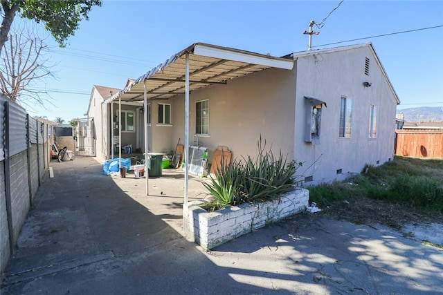 view of front of house featuring crawl space, a patio area, fence, and stucco siding