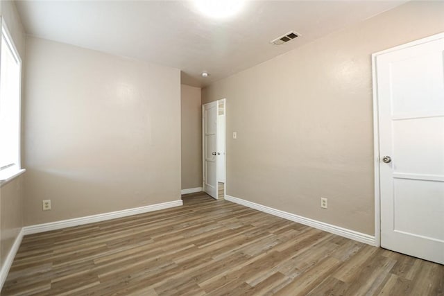 spare room featuring visible vents, baseboards, and wood finished floors