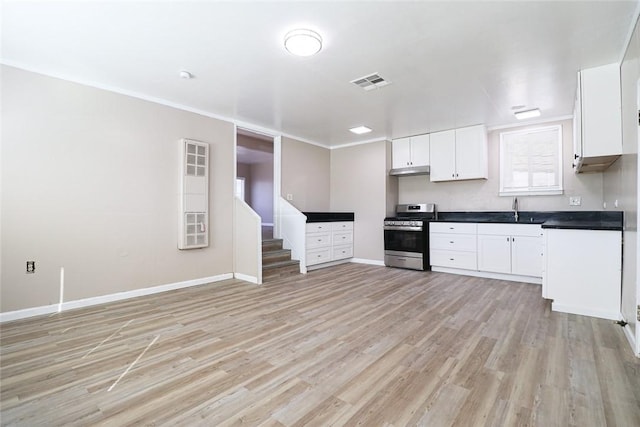 kitchen featuring a sink, white cabinetry, light wood-style floors, dark countertops, and gas range