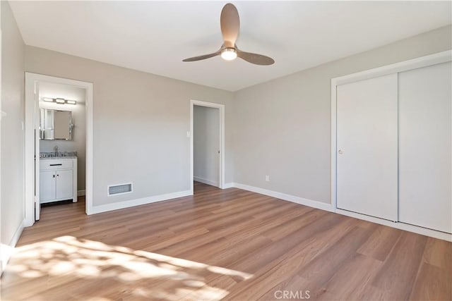 unfurnished bedroom with light wood-style flooring, a closet, visible vents, and baseboards