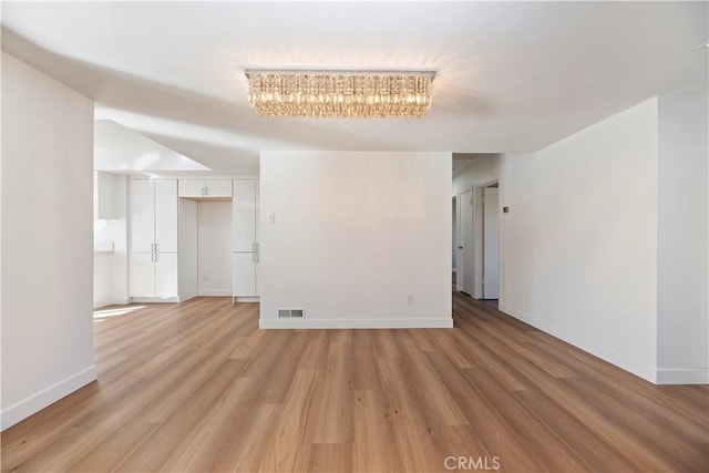 empty room with baseboards, visible vents, and light wood-style floors