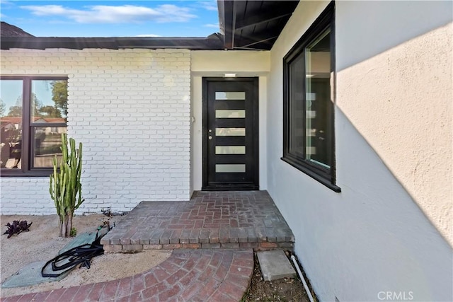 property entrance featuring brick siding and stucco siding