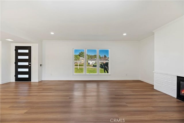 unfurnished living room with a glass covered fireplace, baseboards, recessed lighting, and wood finished floors