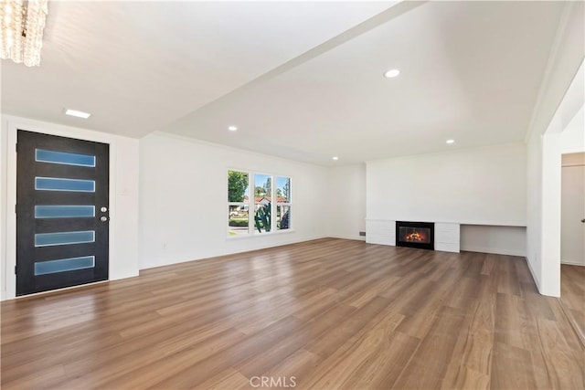 unfurnished living room with wood finished floors, a glass covered fireplace, and recessed lighting