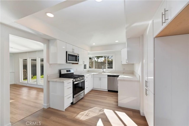 kitchen featuring light countertops, appliances with stainless steel finishes, light wood-style flooring, and white cabinets