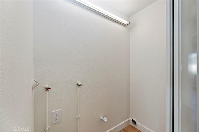 clothes washing area with laundry area, baseboards, and light wood-style floors