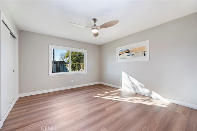 empty room featuring a ceiling fan, light wood-type flooring, and baseboards