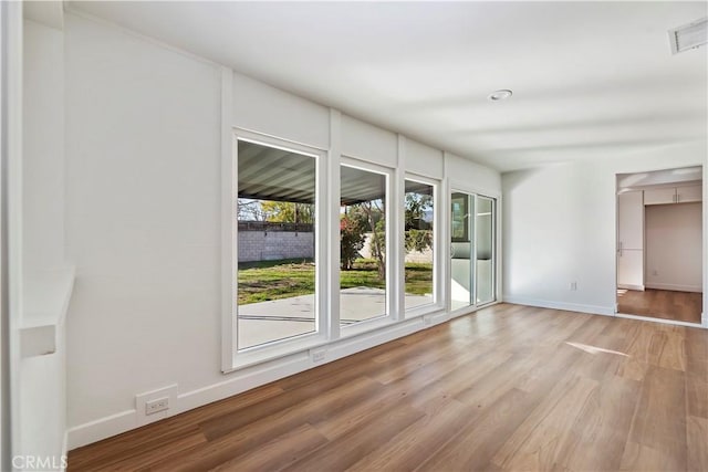 spare room featuring visible vents, light wood-style flooring, and baseboards