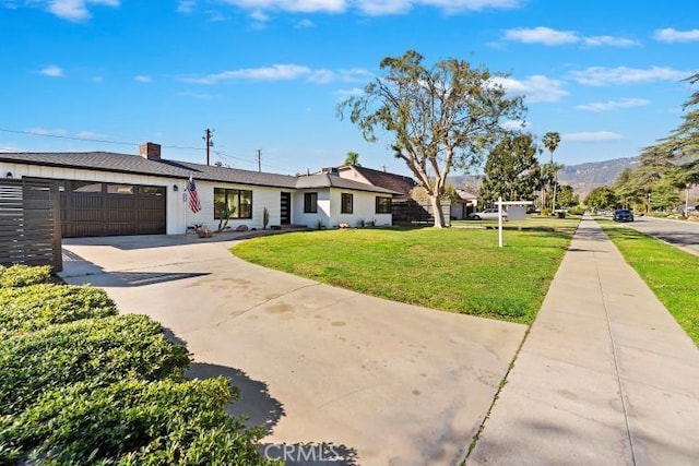 single story home featuring a garage, concrete driveway, and a front yard