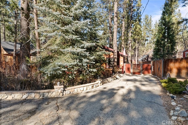 view of front of home with a gate, fence, and aphalt driveway