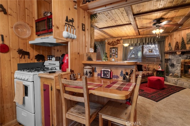 kitchen featuring white gas stove, wooden walls, and under cabinet range hood