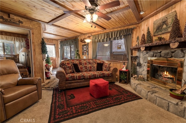 living room with a stone fireplace, wood walls, carpet flooring, and wood ceiling