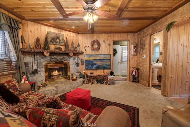 living area featuring carpet floors, wooden ceiling, wooden walls, and a stone fireplace