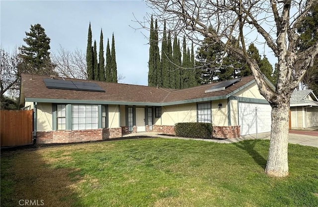 ranch-style house featuring brick siding, stucco siding, a front yard, roof mounted solar panels, and fence