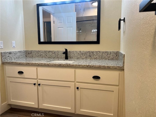 bathroom with a textured wall and vanity