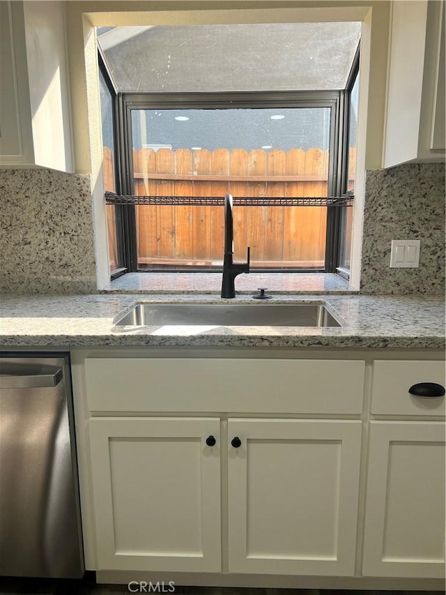 kitchen with dishwasher, a sink, and white cabinets