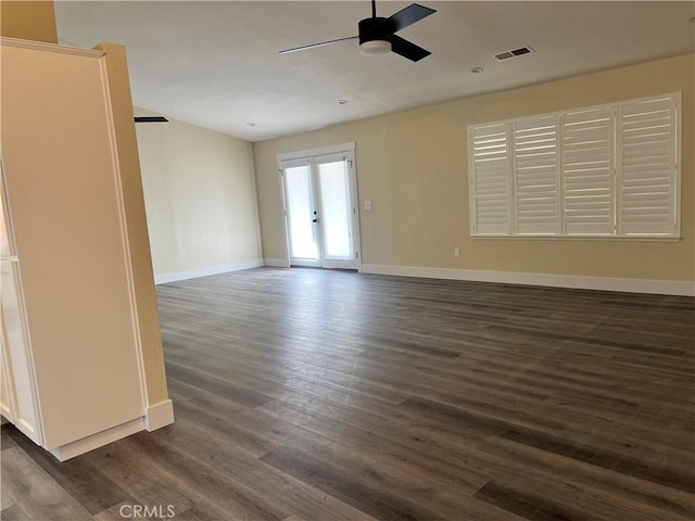 unfurnished room with visible vents, baseboards, dark wood finished floors, ceiling fan, and french doors