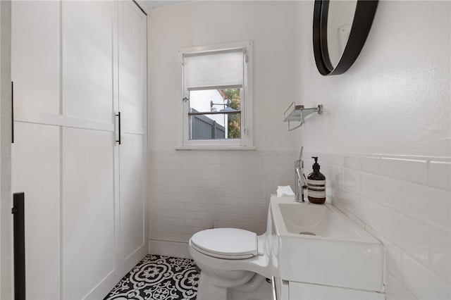 bathroom featuring toilet, vanity, tile walls, wainscoting, and tile patterned floors