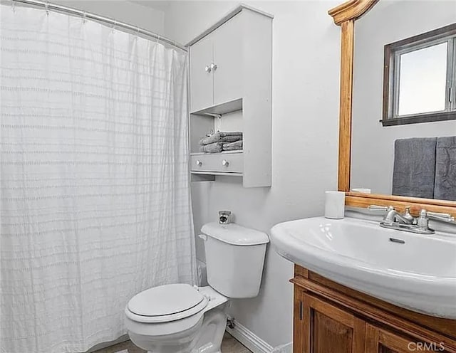 bathroom with curtained shower, baseboards, vanity, and toilet