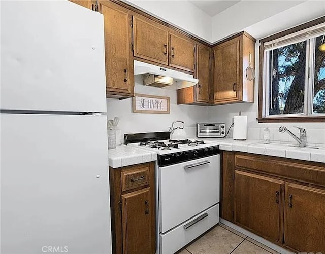 kitchen featuring tile counters, white appliances, a sink, and under cabinet range hood