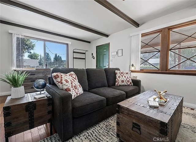 living area with baseboards, plenty of natural light, and beamed ceiling