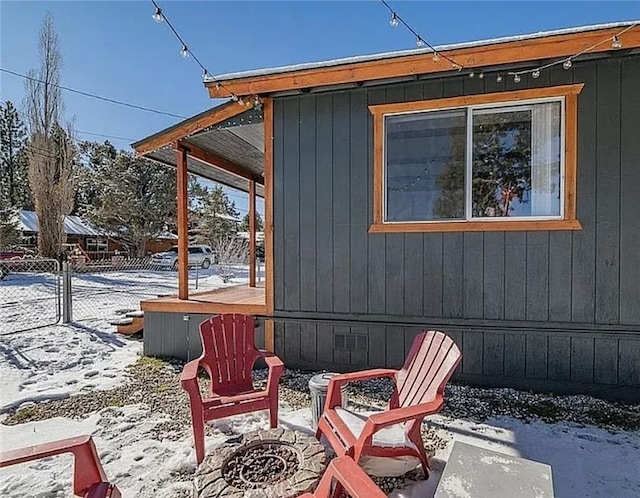 snow covered patio with a fire pit and fence