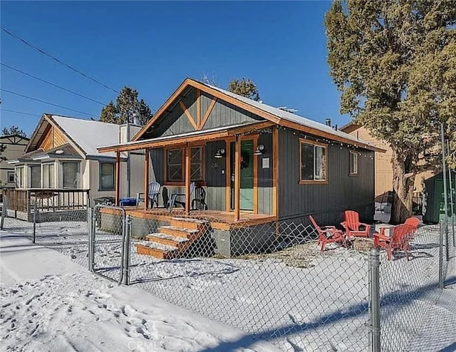 view of front facade featuring covered porch, fence, and a fire pit