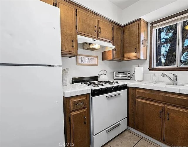 2161 4th Ln, Big Bear City, CA 92314 - kitchen featuring a sink, tile countertops, white appliances, light tile patterned floors, and under cabinet range hood