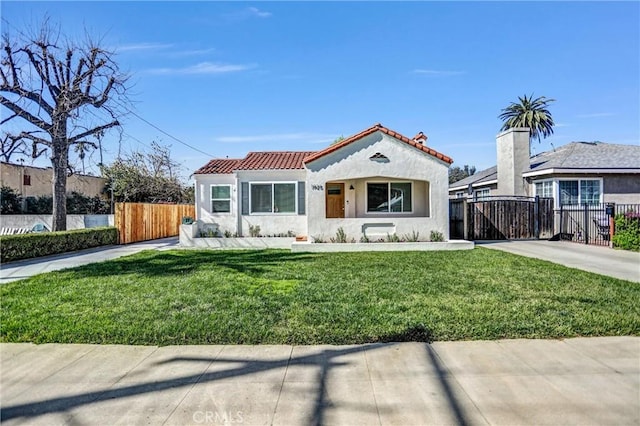 mediterranean / spanish-style house featuring a tile roof, stucco siding, a gate, fence, and a front lawn